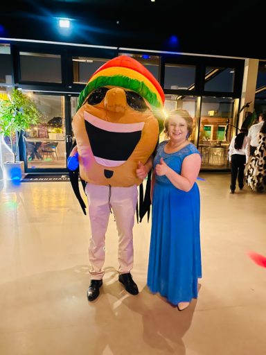 Eine Person im bunten Kostüm und eine Frau in einem blauen Kleid stehen zusammen.