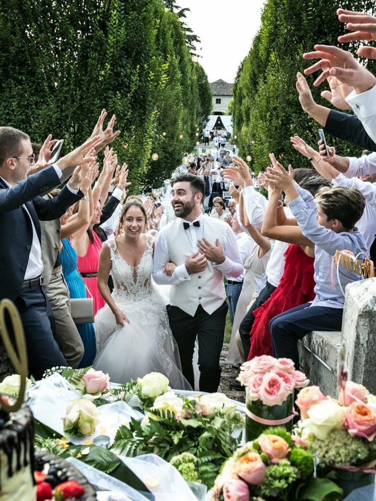 Brautpaar verlässt die Zeremonie, umgeben von jubelnden Gästen und Hochzeitsdekor.