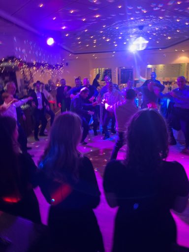 Tanzende Menschen auf einer Party mit bunten Lichtern und festlicher Atmosphäre.