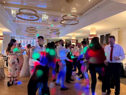 Tanzende Menschen auf einer festlichen Veranstaltung mit bunten Lichtern und Dekoration.