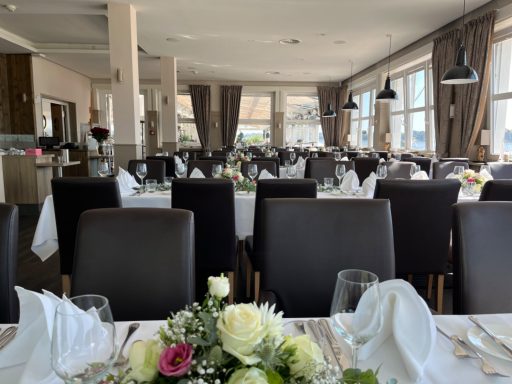 Elegante Restaurant mit gedeckten Tischen und Blumenschmuck.