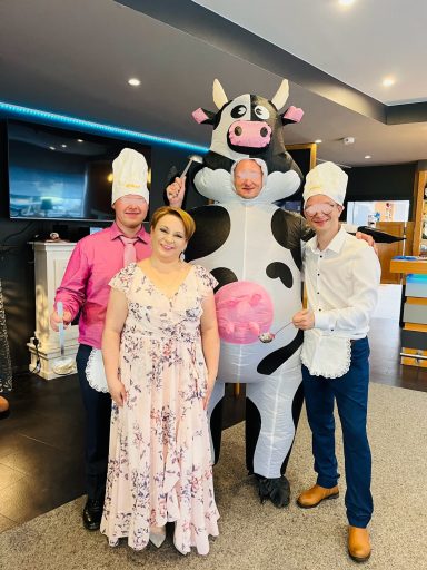 Vier Personen posieren, zwei tragen Kühen und zwei Käppchen, in einem modernen Raum.