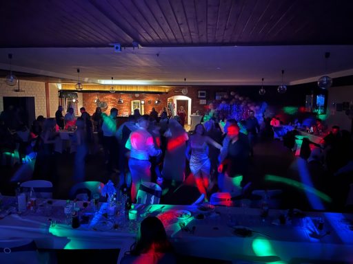 Menschen tanzen in einem beleuchteten Raum mit bunten Lichtern.